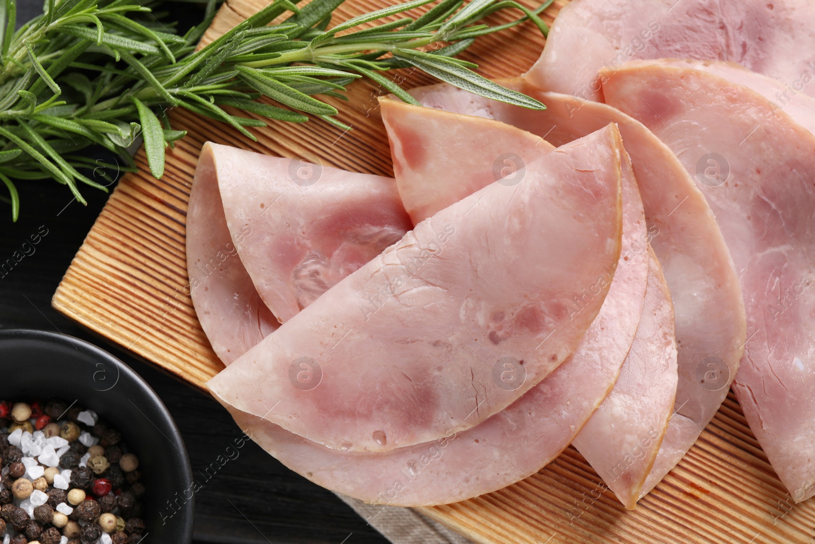 Photo of Slices of delicious ham with rosemary and spices on dark wooden table, flat lay