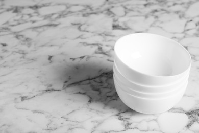 Photo of Stack of empty ceramic bowls on white marble table, space for text