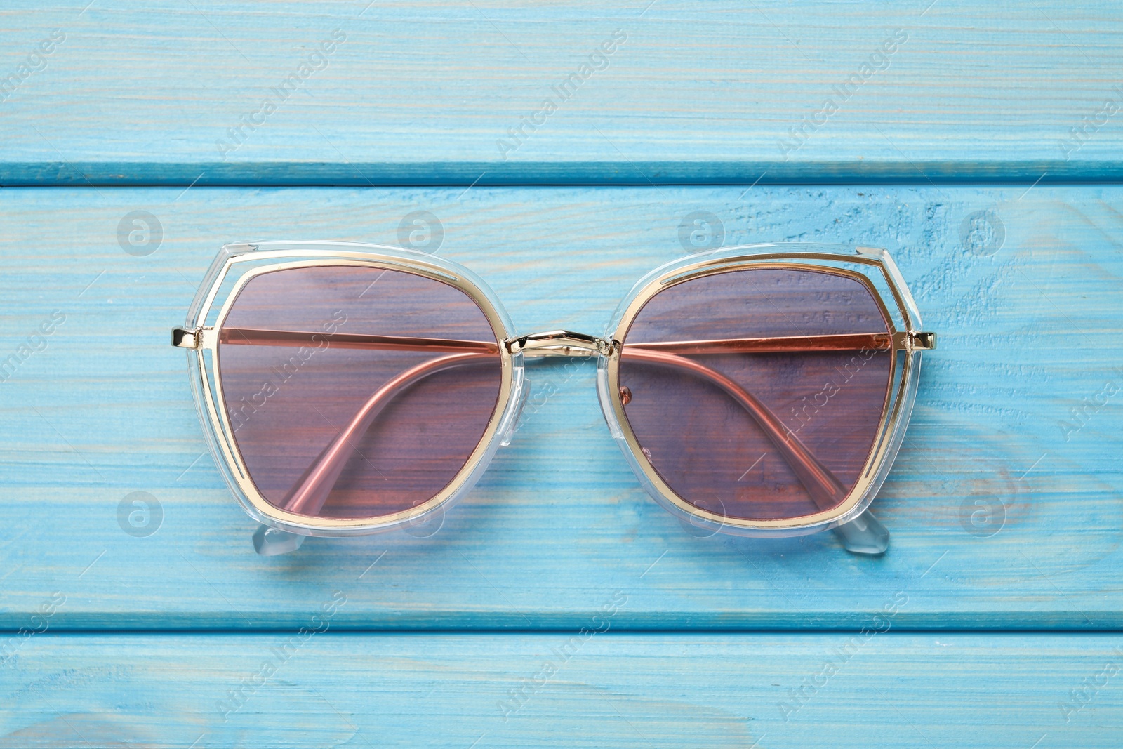 Photo of New stylish sunglasses on turquoise wooden table, top view