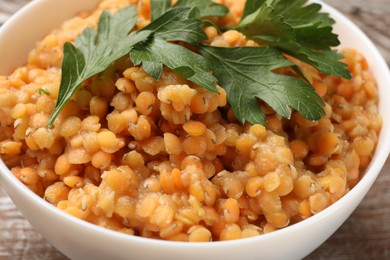 Photo of Delicious red lentils with parsley in bowl on table, closeup