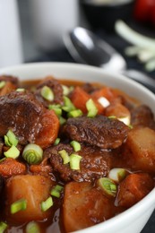 Photo of Delicious beef stew with carrots, green onions and potatoes, closeup