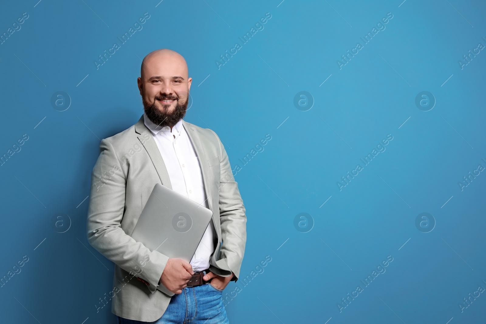 Photo of Portrait of confident young businessman with laptop on color background