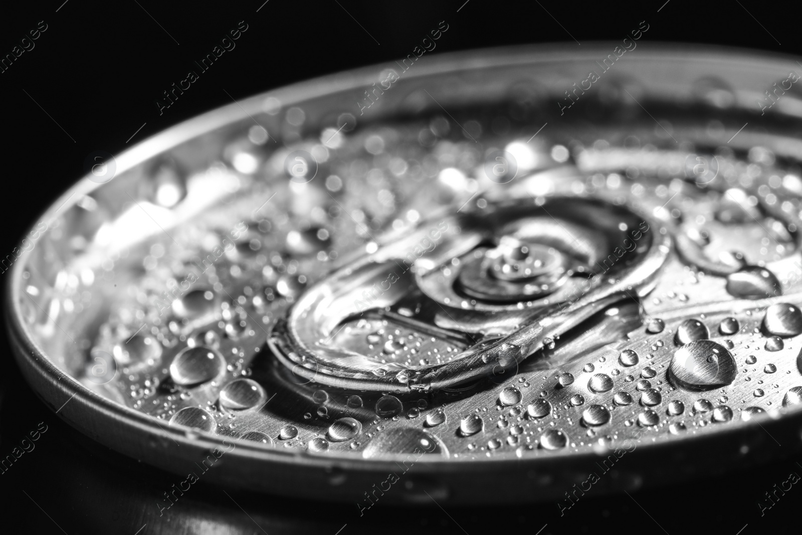 Photo of Aluminum can of beverage covered with water drops on black background, closeup