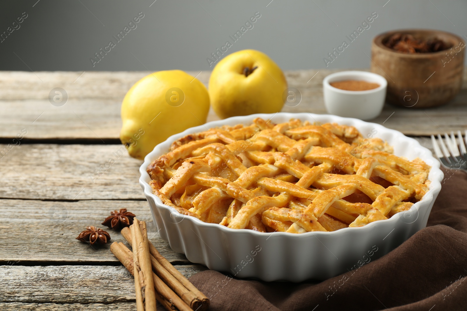 Photo of Tasty homemade quince pie with spices on wooden table. closeup