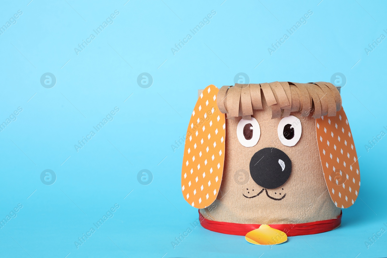 Photo of Toy dog made of toilet paper roll on light blue background. Space for text