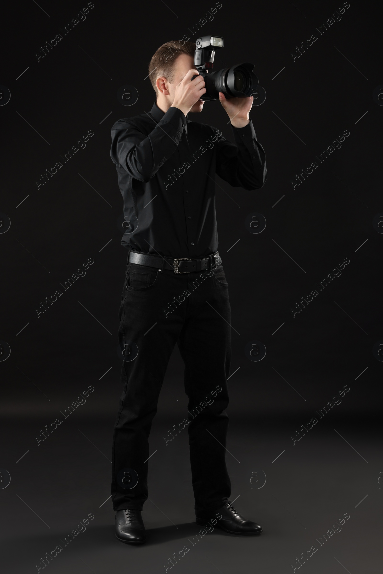 Photo of Professional photographer taking picture on black background