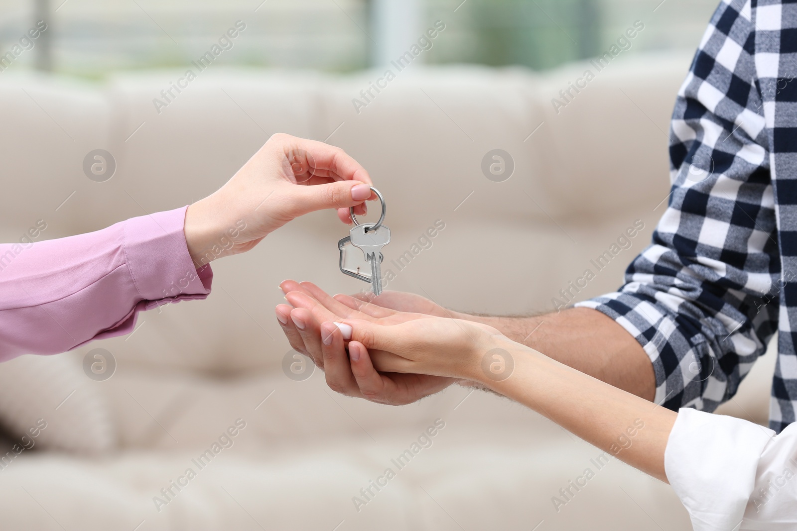 Photo of Real estate agent giving house key to couple indoors, closeup