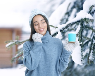 Image of Happy beautiful woman with mulled wine outdoors on snowy day 