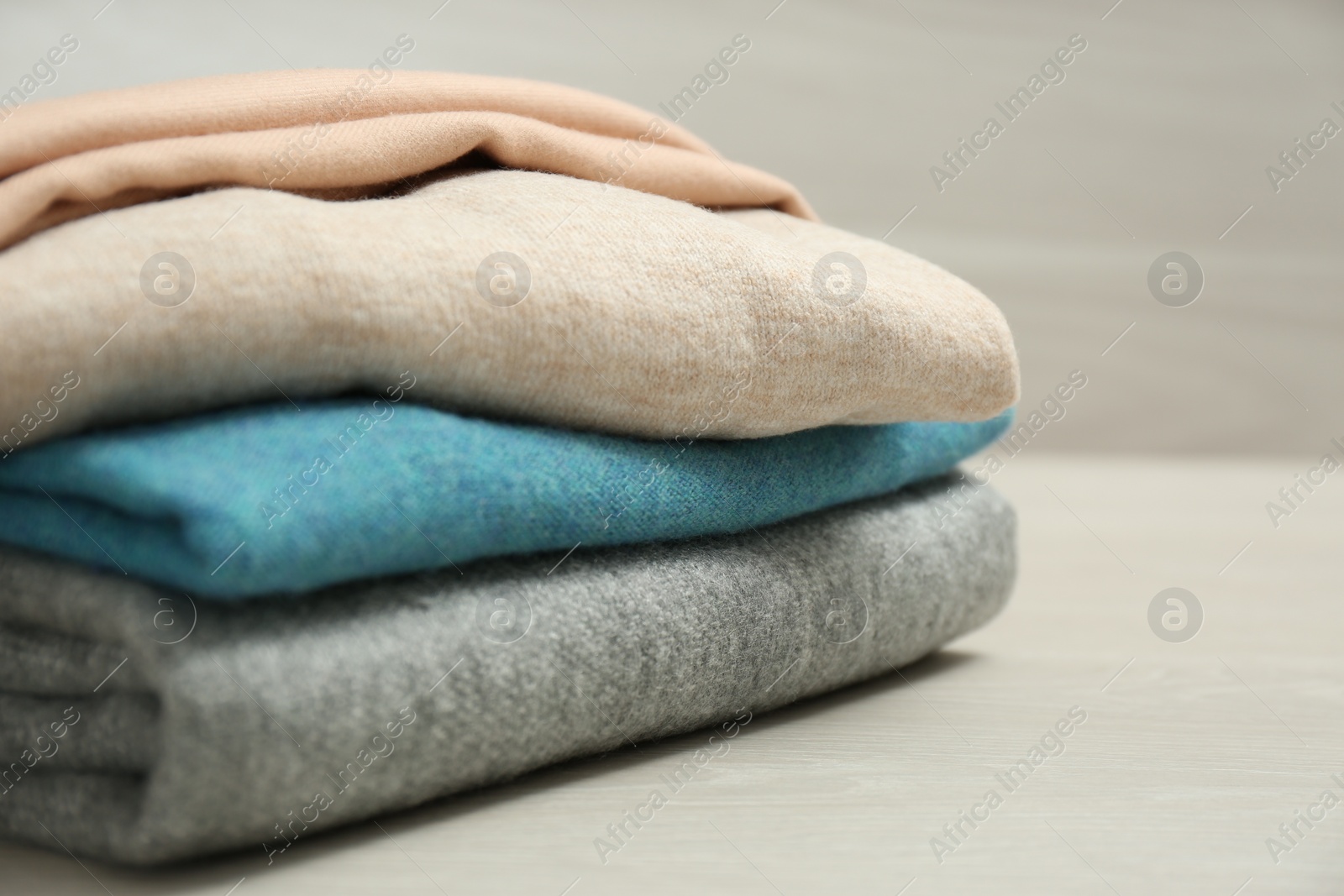 Photo of Stack of cashmere clothes on wooden table, closeup