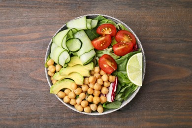 Photo of Tasty salad with chickpeas and vegetables on wooden table, top view