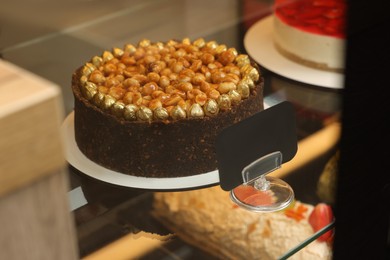 Delicious cake with nuts on counter in store, closeup