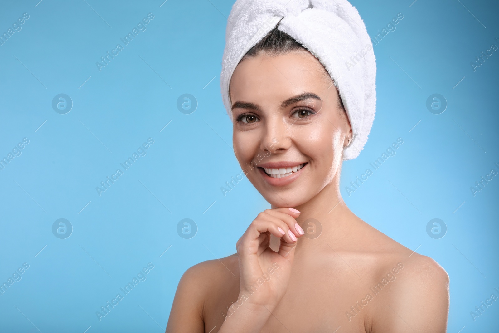 Photo of Happy young woman with towel on head against light blue background, space for text. Washing hair