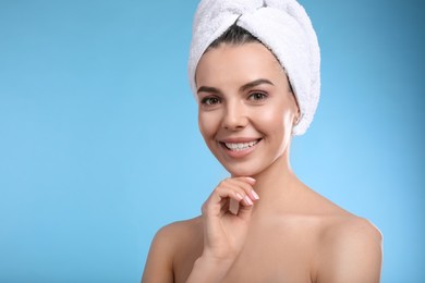 Happy young woman with towel on head against light blue background, space for text. Washing hair