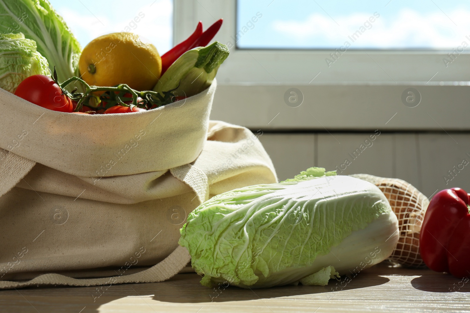 Photo of Fresh Chinese cabbage and other products on wooden table indoors