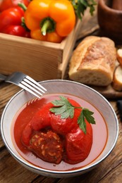 Photo of Delicious stuffed pepper with parsley in bowl on wooden table