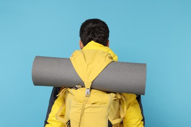 Photo of Man with backpack on light blue background, back view. Active tourism