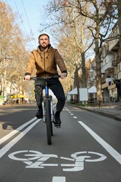 Happy handsome man riding bicycle on lane in city