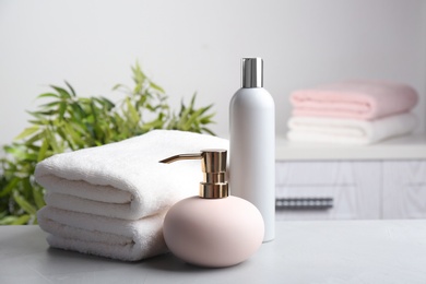 Fresh towels and toiletries on light grey stone table. Space for text