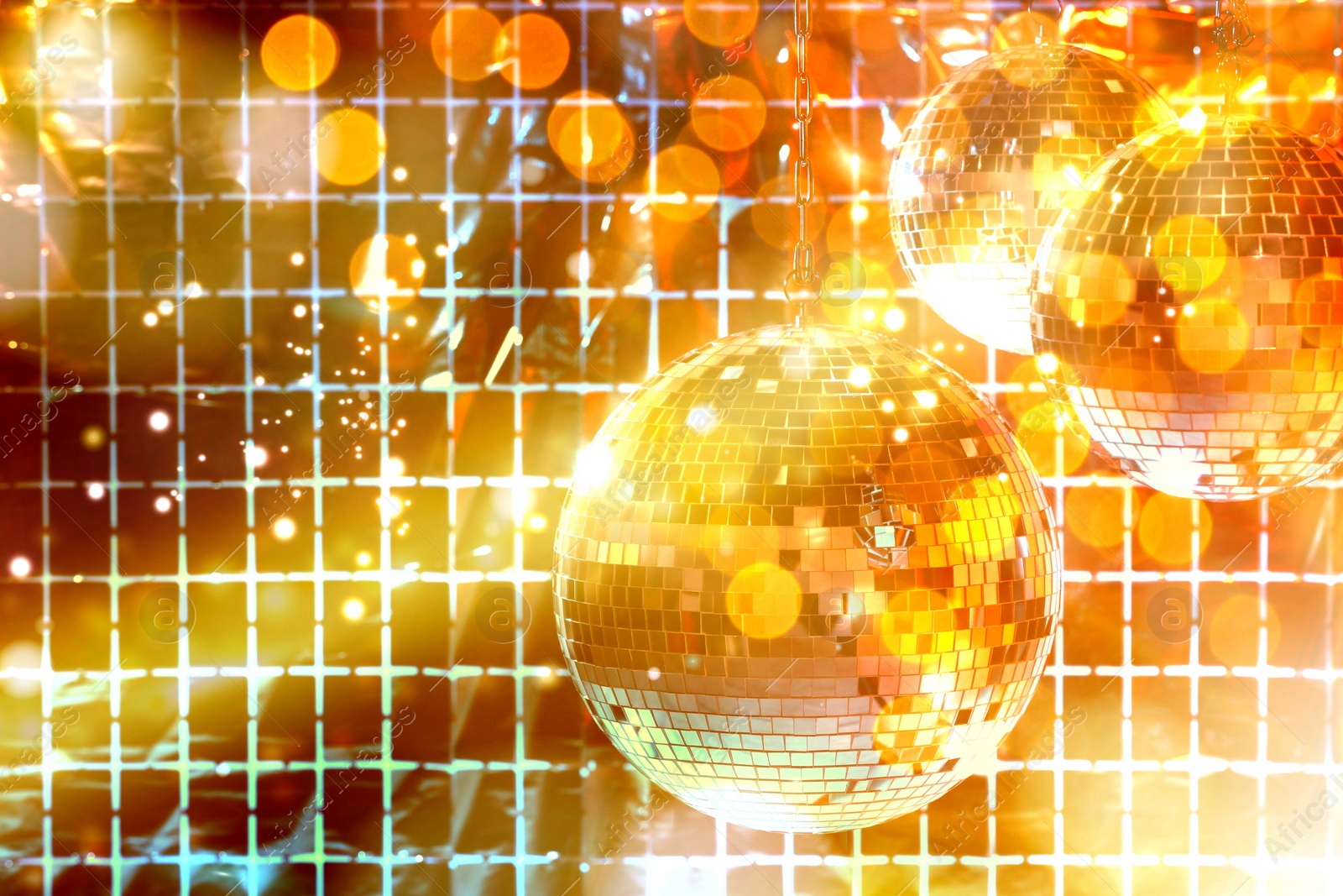 Image of Shiny disco balls against foil party curtain under golden lights, space for text. Bokeh effect