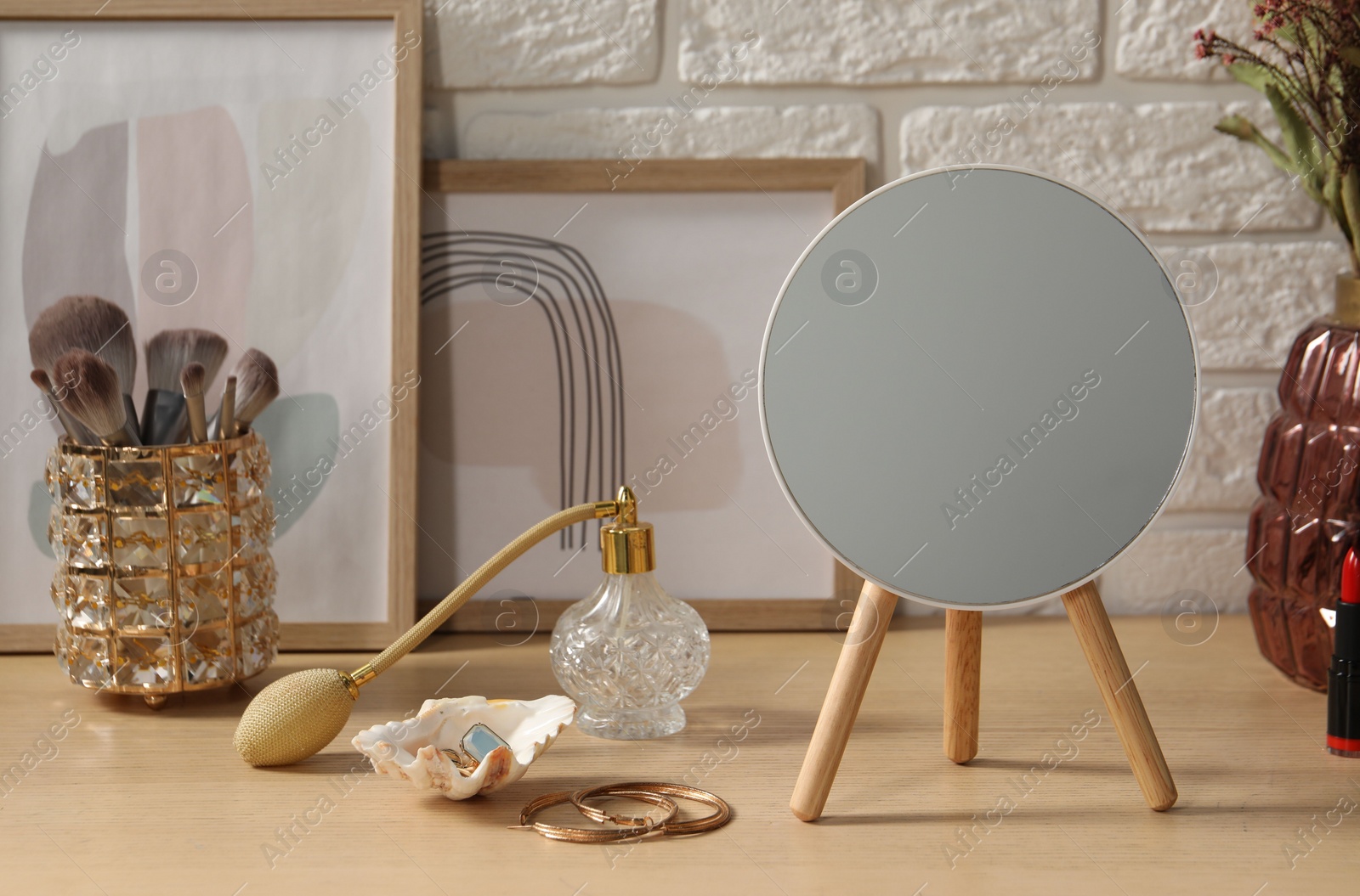 Photo of Mirror, jewelry and perfume on wooden dressing table