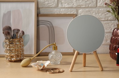 Mirror, jewelry and perfume on wooden dressing table