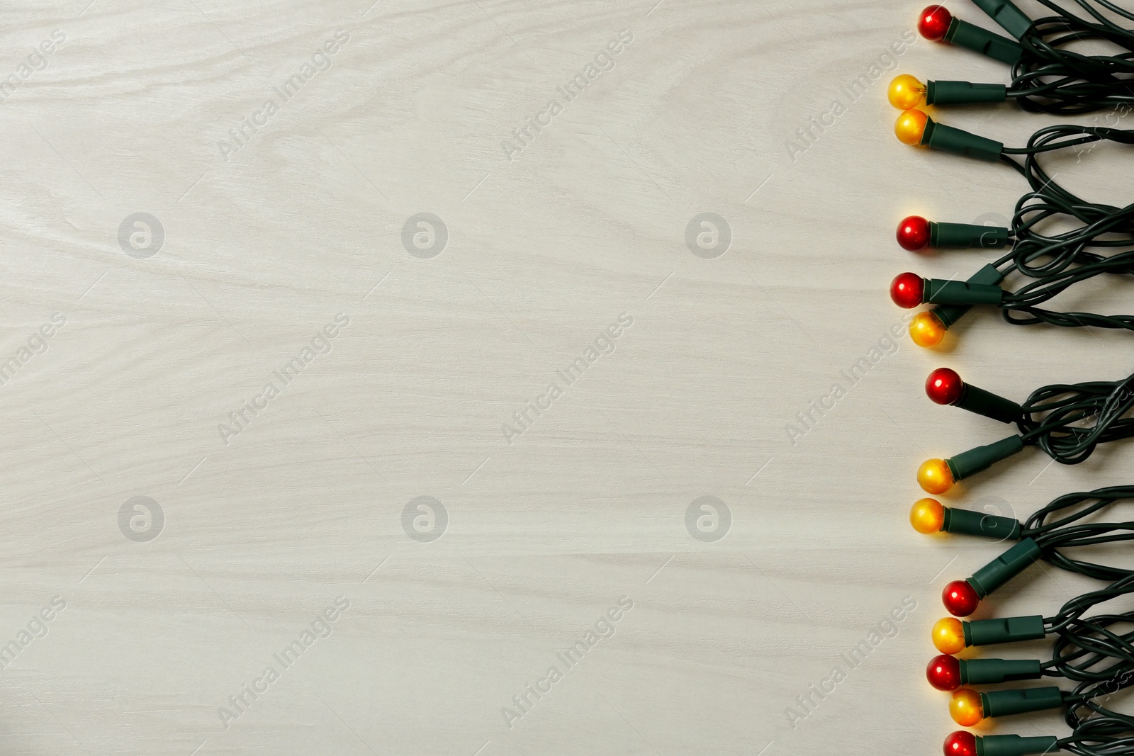 Photo of Beautiful glowing Christmas lights on white wooden background, top view. Space for text