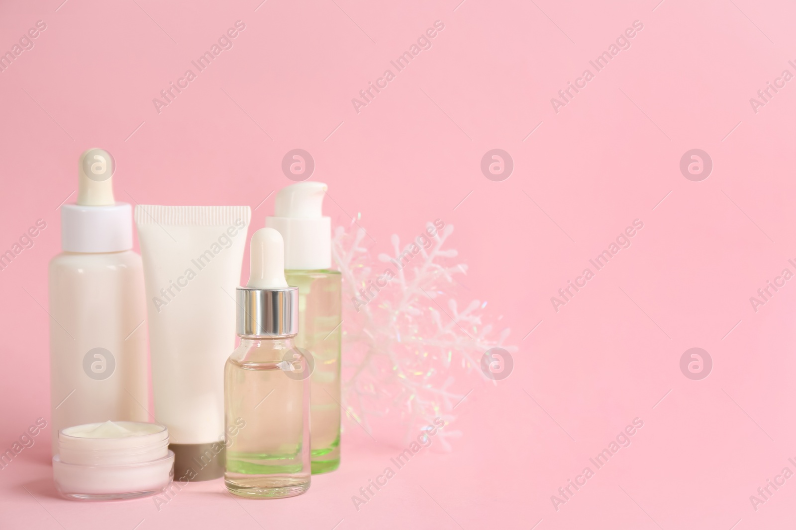 Photo of Beautiful composition with cosmetic products on pink background, space for text. Winter care
