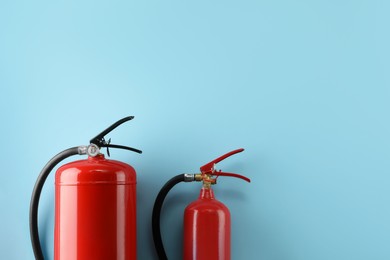 Photo of Different fire extinguishers on light blue background, flat lay. Space for text