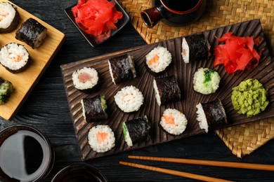 Photo of Tasty sushi rolls served on black wooden table, flat lay
