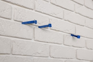 Decorative white bricks with tile leveling system on wall, closeup