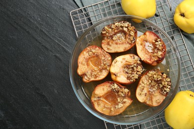 Photo of Tasty baked quinces with walnuts and honey in bowl on black table, flat lay. Space for text