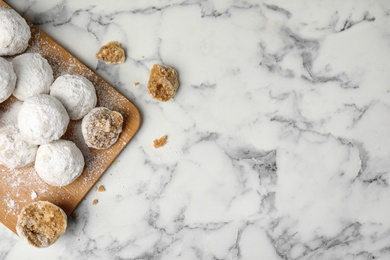 Photo of Christmas snowball cookies on white marble table, flat lay. Space for text