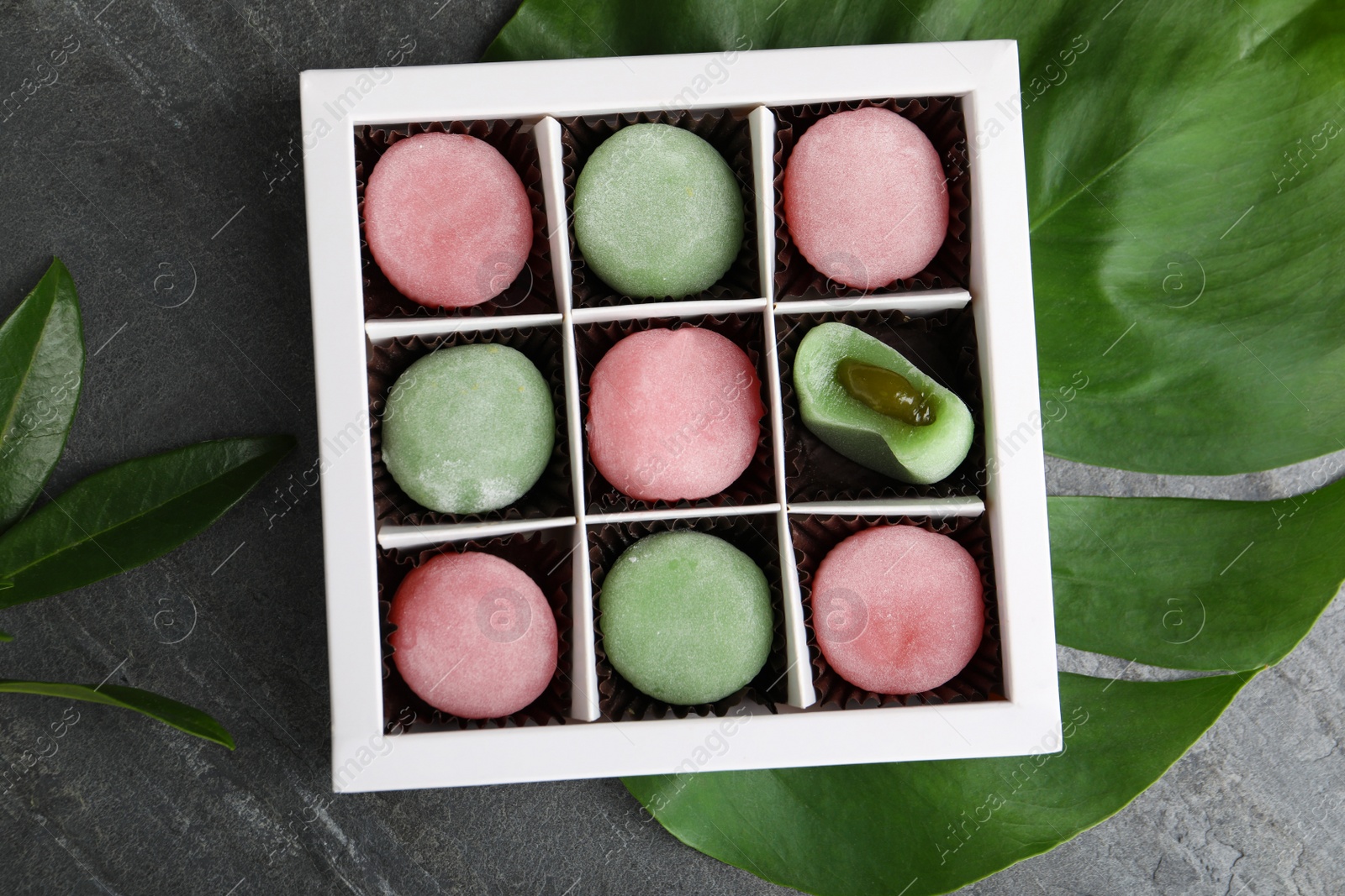 Photo of Box with different delicious mochi on grey table, top view
