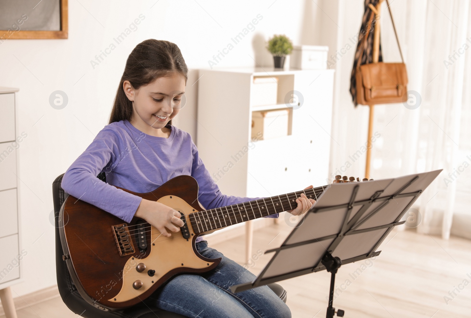 Photo of Little girl playing guitar at music lesson. Learning notes