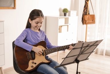 Little girl playing guitar at music lesson. Learning notes