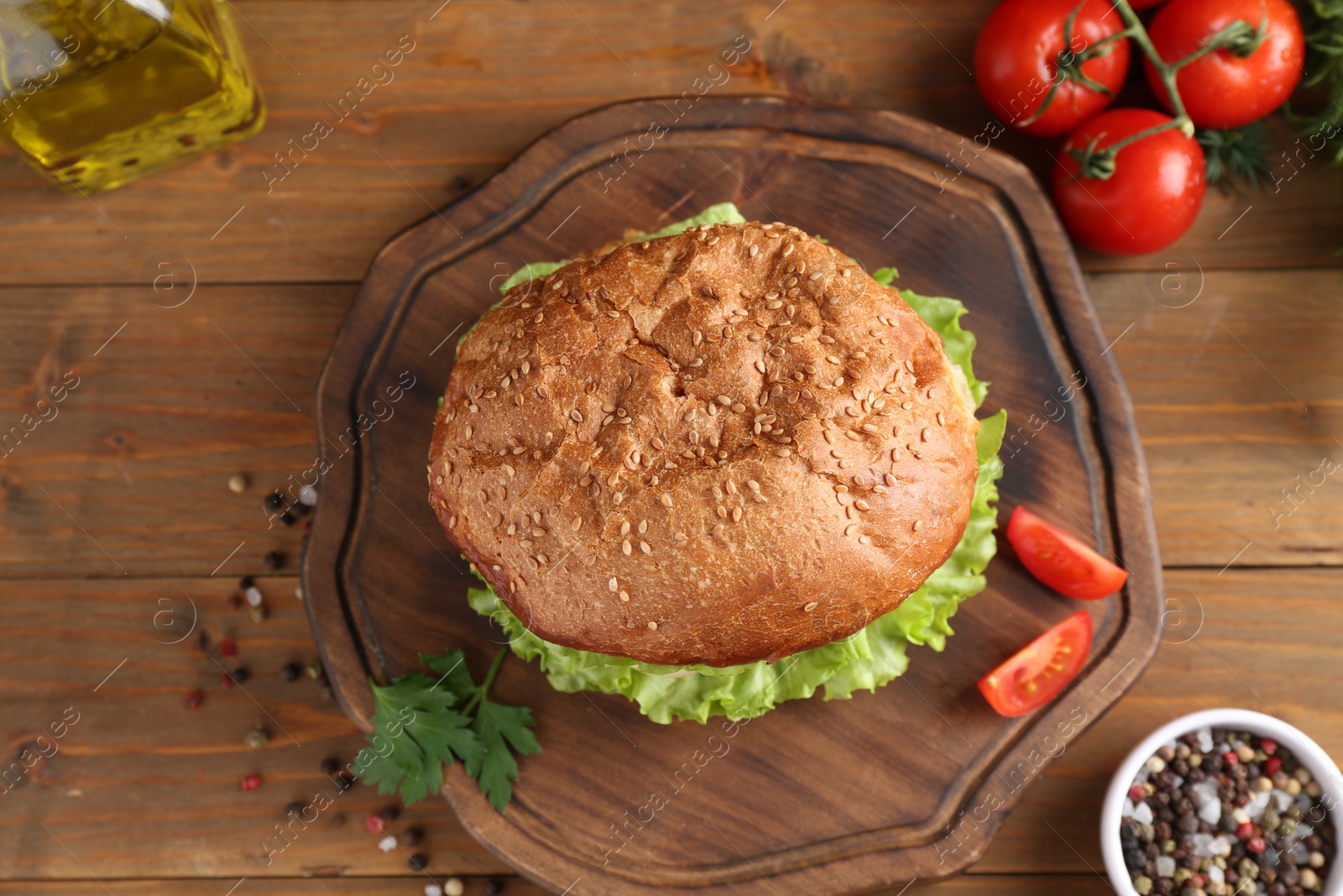 Photo of Delicious vegetarian burger served on wooden table, flat lay