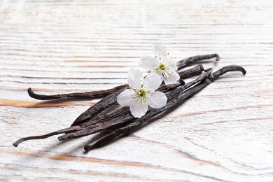 Photo of Vanilla sticks and flowers on wooden background