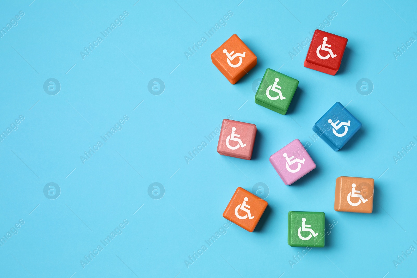 Image of Inclusion concept. Colorful cubes with international symbols of access on light blue background, top view