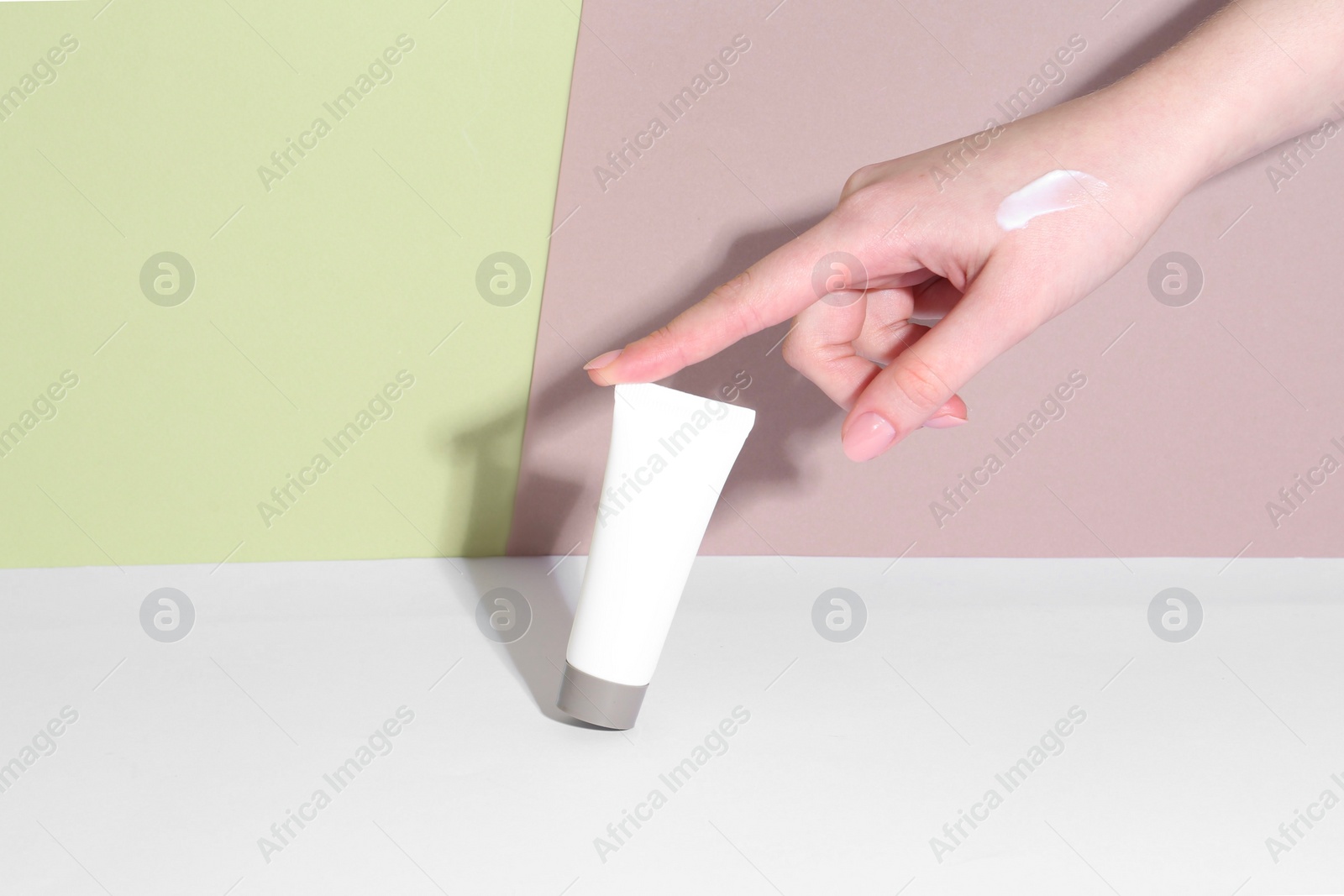 Photo of Woman with tube of cream on color background, closeup