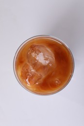 Glass of iced coffee on white table, top view