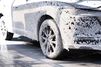 Modern automobile covered with foam at car wash