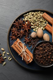 Dishware with different spices and nuts on gray table, top view