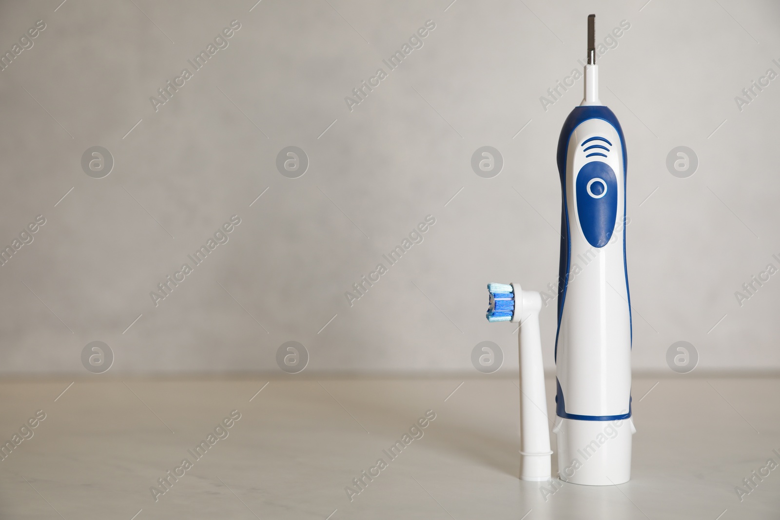 Photo of Electric toothbrush on light background, space for text