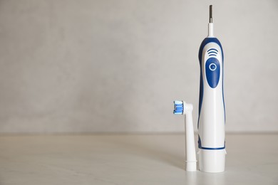 Photo of Electric toothbrush on light background, space for text