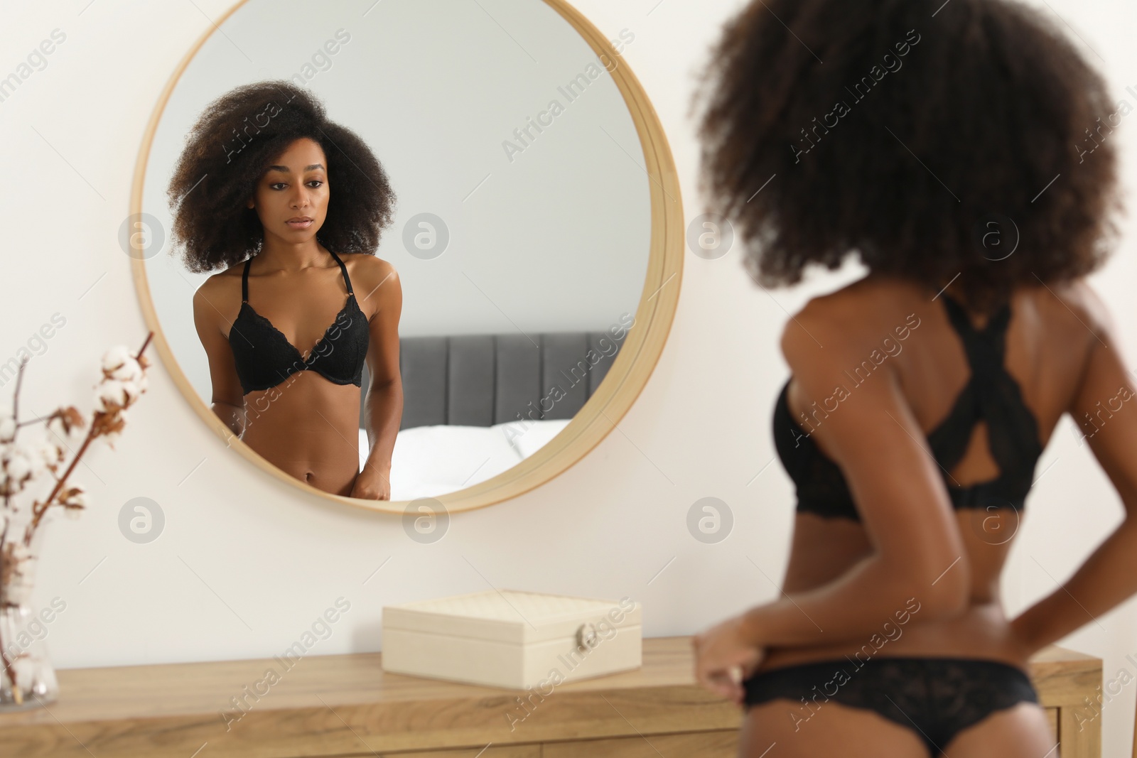 Photo of Beautiful woman in elegant black underwear near mirror indoors