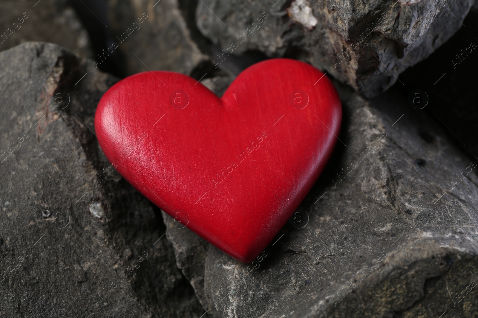 Photo of One red decorative heart on stones, closeup