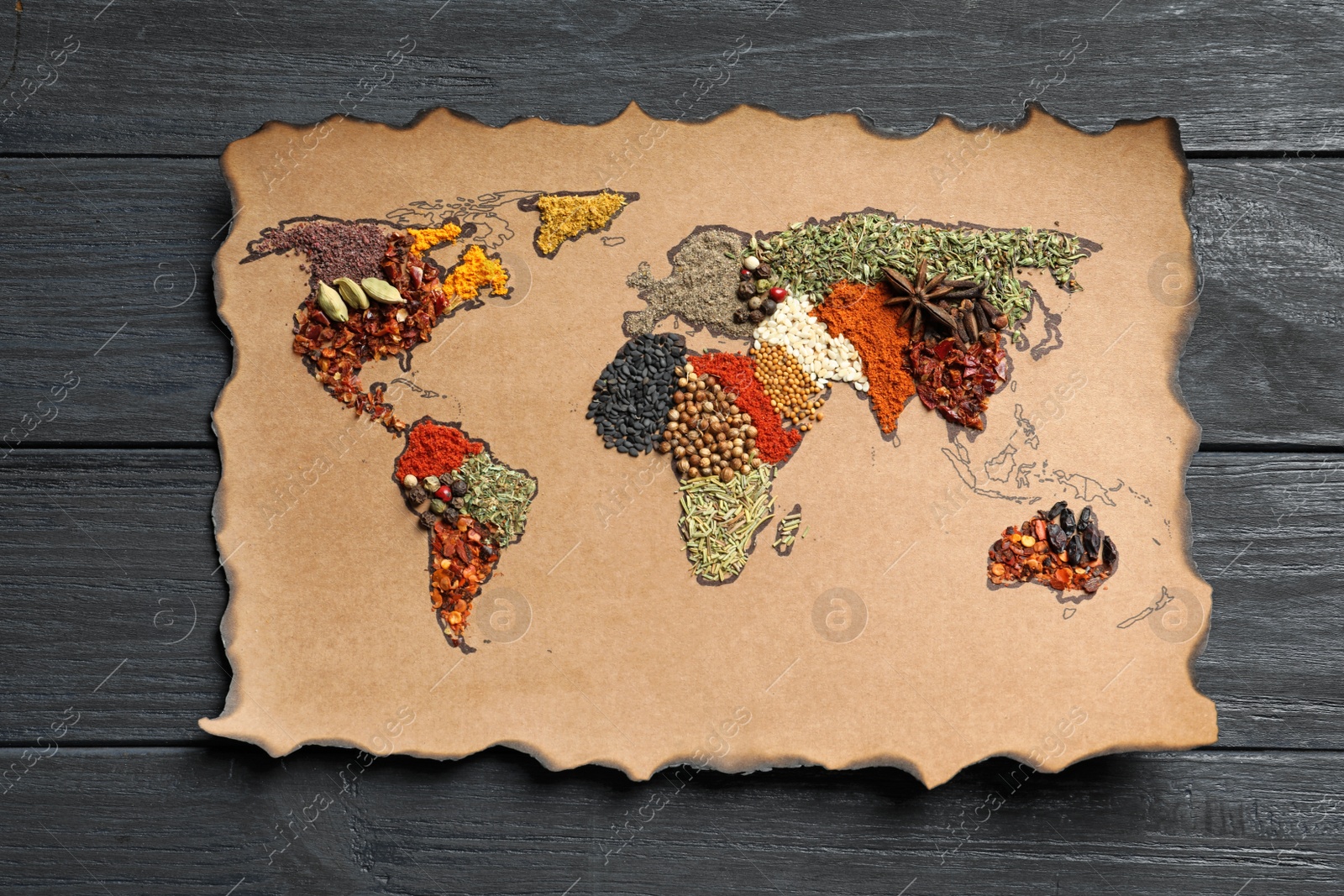 Photo of Paper with world map made of different aromatic spices on wooden background, top view