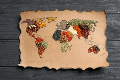 Paper with world map made of different aromatic spices on wooden background, top view