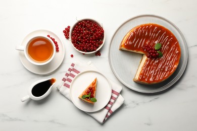 Photo of Delicious caramel cheesecake with red currants and mint served on white marble table, flat lay