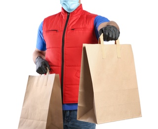 Photo of Courier in medical mask holding paper bags with takeaway food on white background, closeup. Delivery service during quarantine due to Covid-19 outbreak